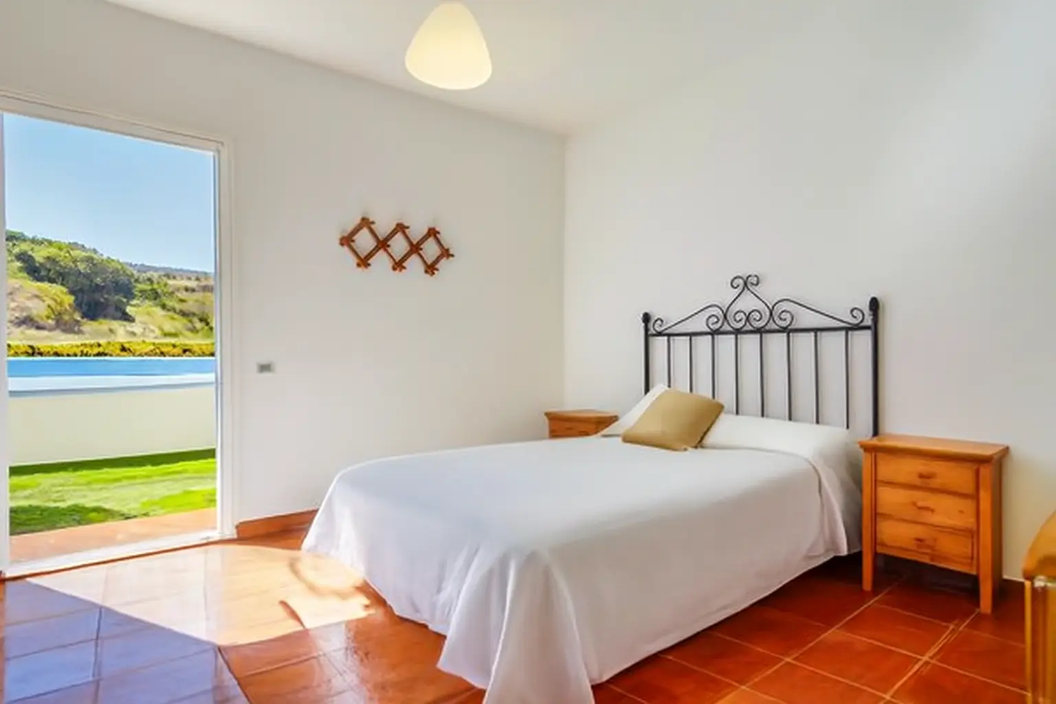 Schlafzimmer mit Terrassentür und Blick auf Pool und Grün