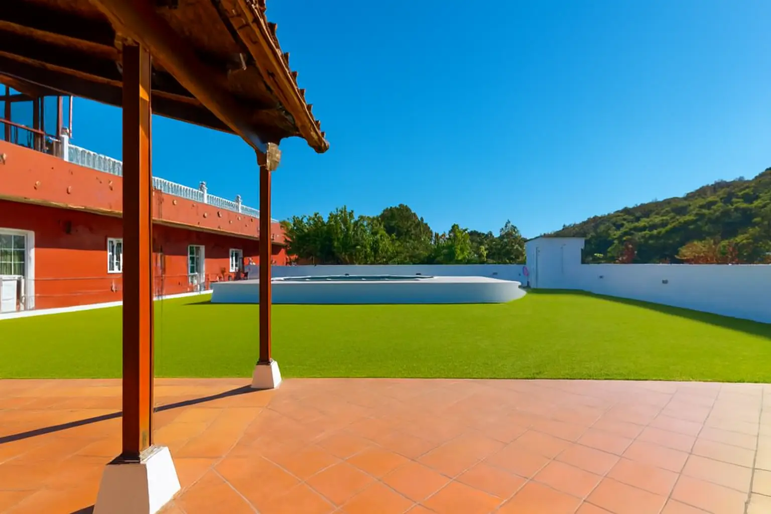 Terrasse mit Blick auf Pool, Rasen und rotes Haupthaus