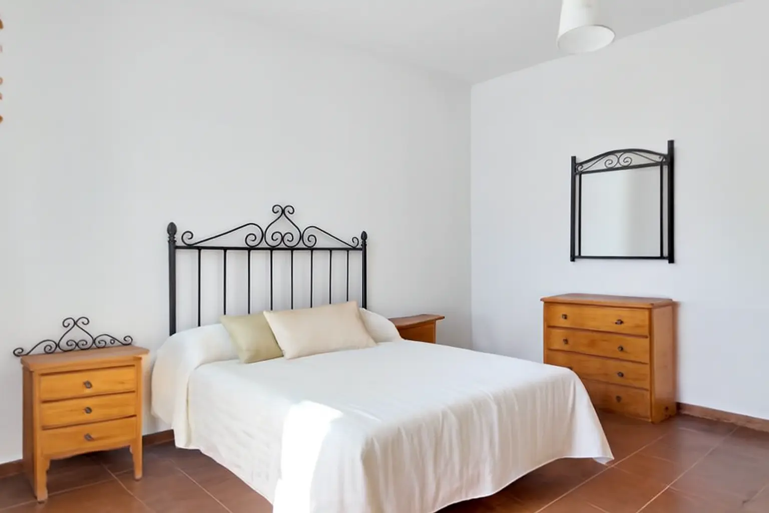 Helles Schlafzimmer mit Doppelbett, Kommode und Wandspiegel