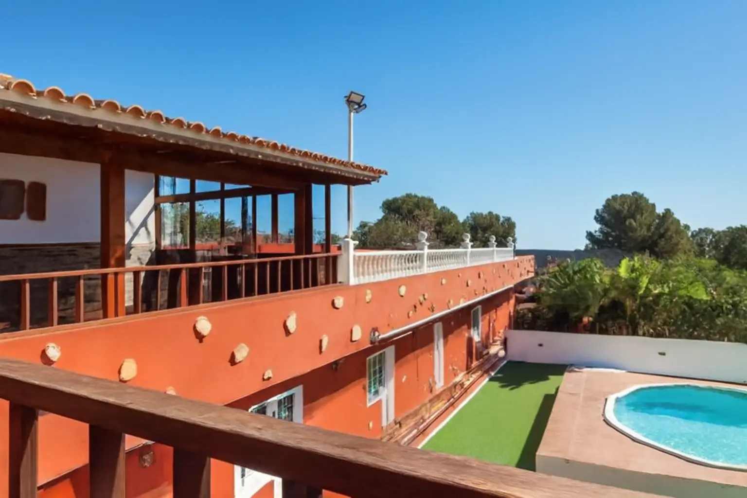 Blick vom Balkon auf Pool und Kunstrasen