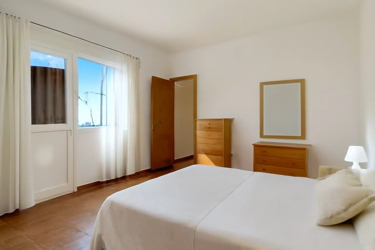 Schlafzimmer mit Balkontür, Kommode und Doppelbett