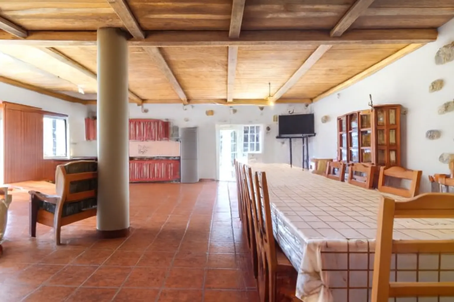 Veranstaltungsraum mit langer Tafel und Küche im Hintergrund