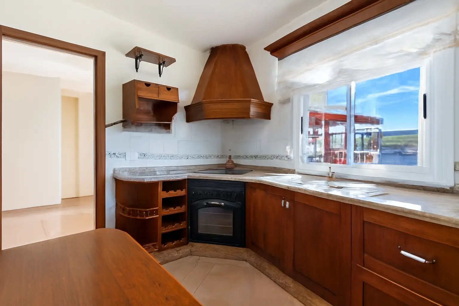 Küche mit Holzschränken, Abzugshaube und Fensterblick