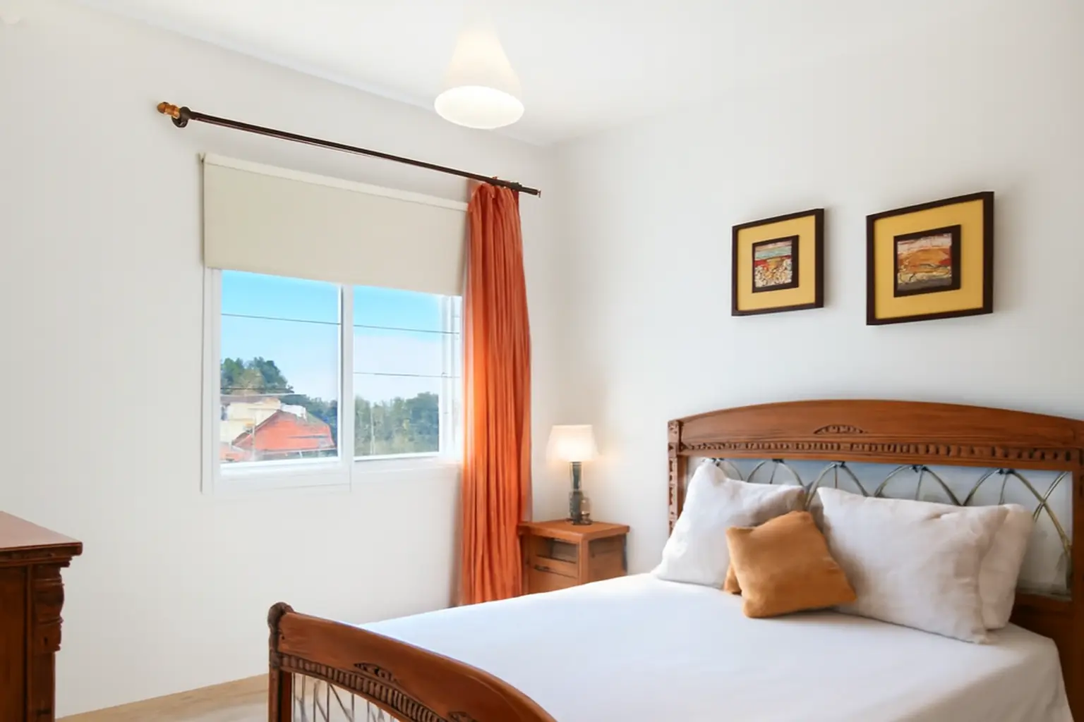 Schlafzimmer mit klassischem Holzbett und orangen Vorhängen